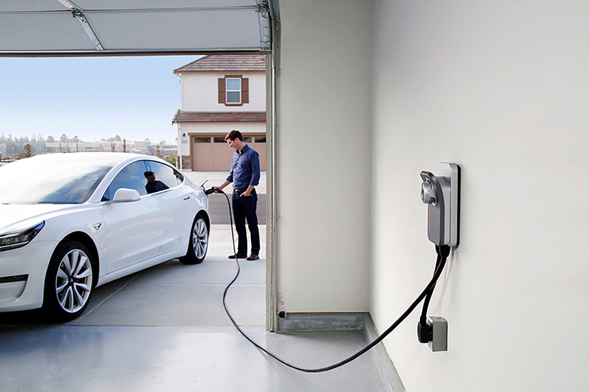 A man using a home EV charging station to charge his electric vehicle in his garage
