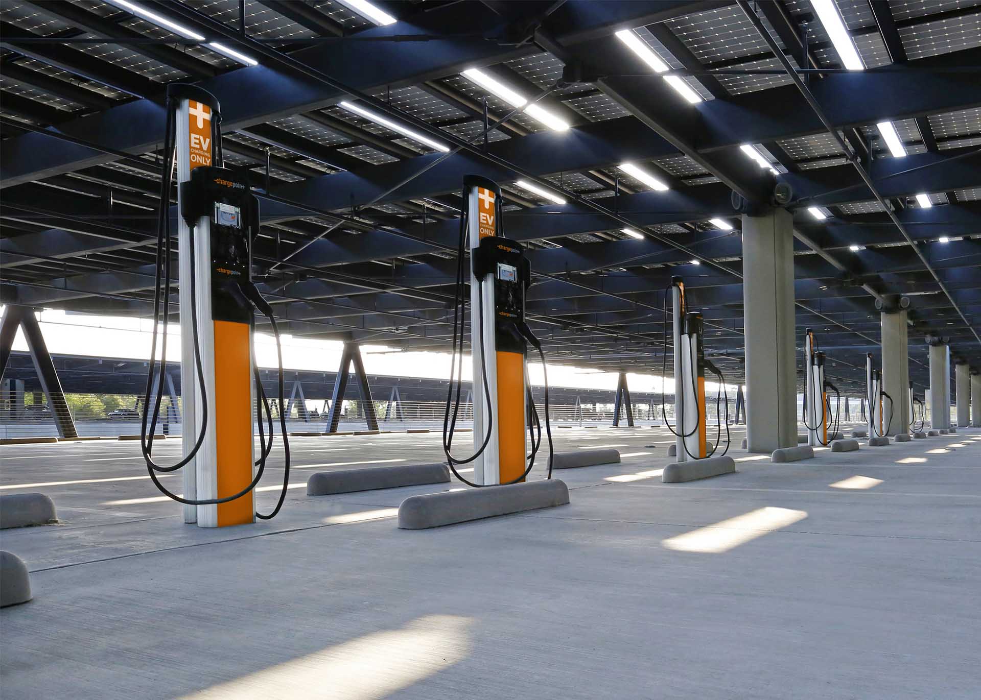 A group of EV charging stations in front of retail parking garage spaces