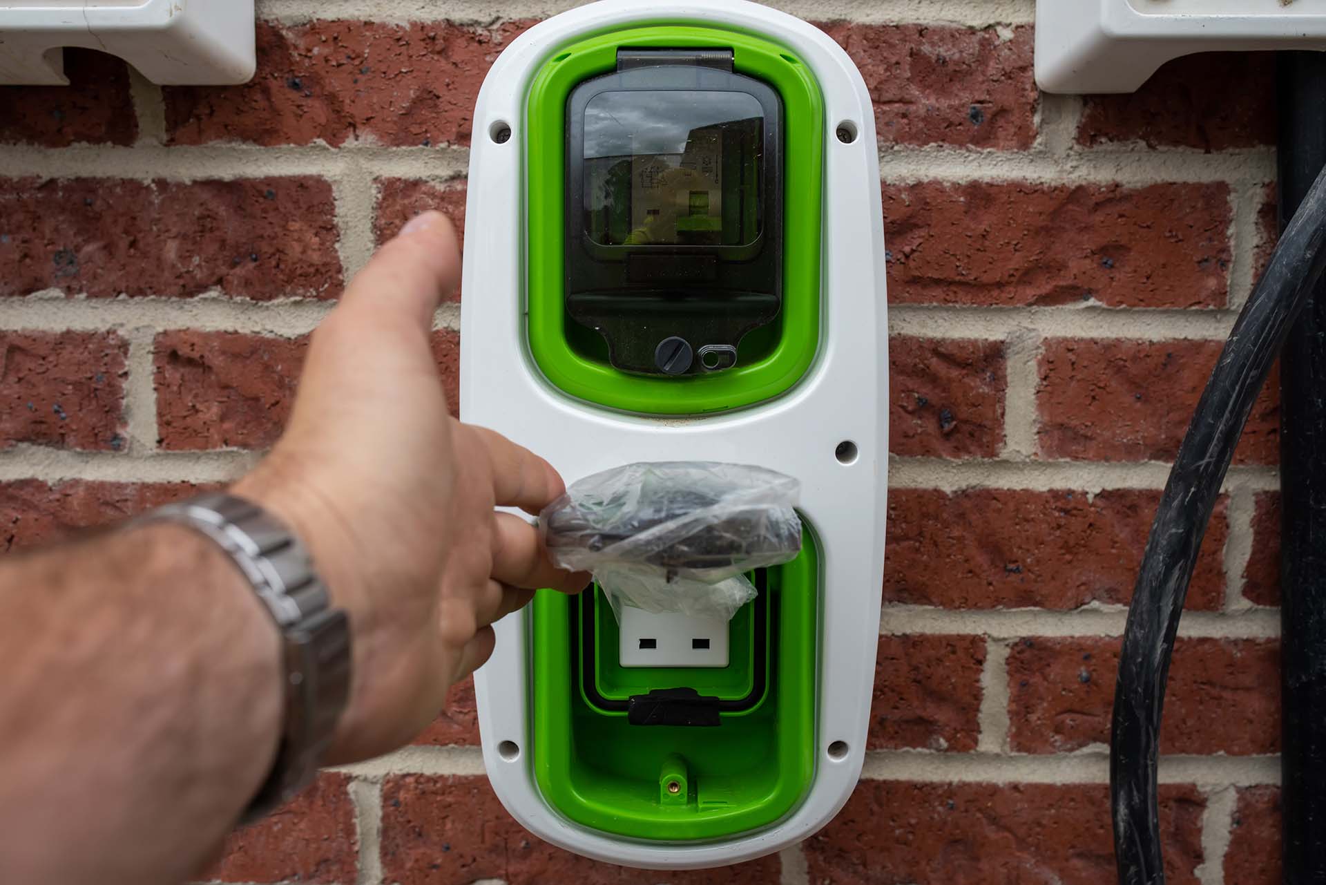 Electric vehicle domestic charging point installed outside of the house on new housing development as part of green energy program to allow recharging vehicle overnight