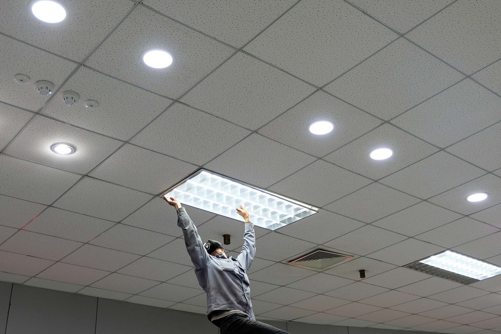 Maintenance man changing light bulbs in office
